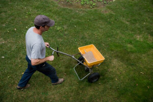 A man making sure to fertilize and seed his lawn