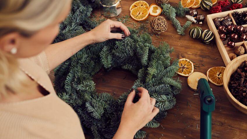 woman making a holiday wreath from seasonal evergreen branches