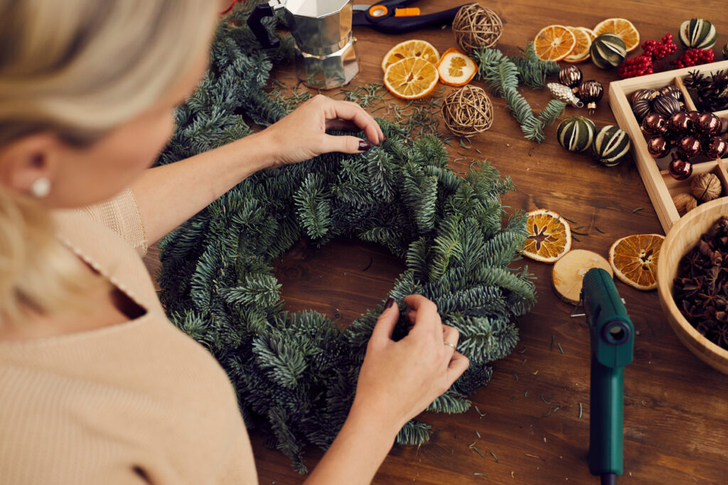 woman making a holiday wreath from seasonal evergreen branches