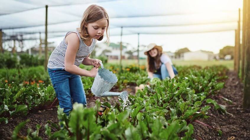 Mom and daughter watering vegetable garden